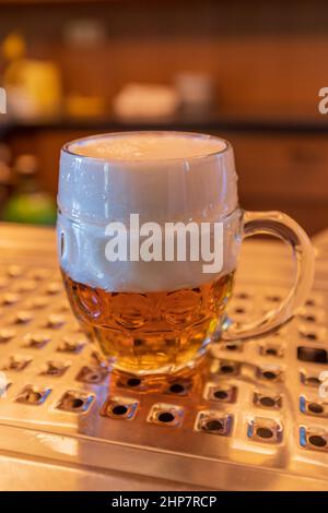 Bier vom Fass im Pulliter - schnyt. Kleines Bier in einem großen Glas. Stockfoto