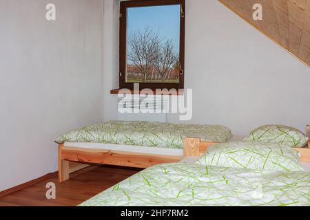 Zimmer mit zwei Betten, weißen Wänden und Fenster mit Blick auf den Weinberg. Stockfoto