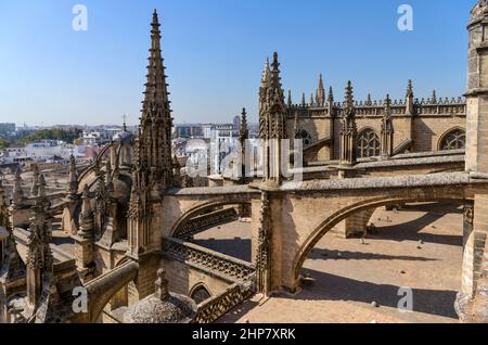 Kathedrale von Sevilla - Eine Weitwinkelansicht der architektonischen Elemente - Zinnen, Strebepfeiler und fliegende Strebepfeiler auf dem Dach der Kathedrale von Sevilla, Spanien. Stockfoto