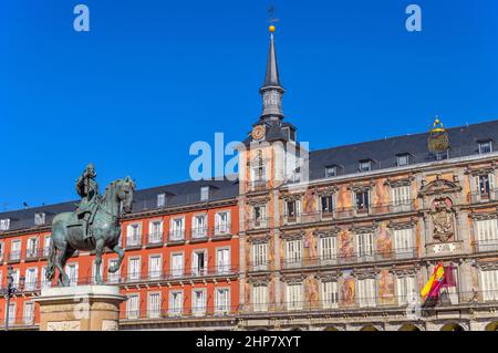 Plaza Mayor - Sonniger Herbstblick auf die Reiterstatue von Philip III, die vor einem der umliegenden Gebäude der Plaza Mayor steht. Madrid, Spanien. Stockfoto