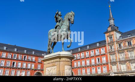 Plaza Mayor - die bronzene Reiterstatue von Philip III, die im Zentrum der Plaza Mayor, Madrid, Spanien, steht, strahlt im Herbst helles Sonnenlicht. Stockfoto