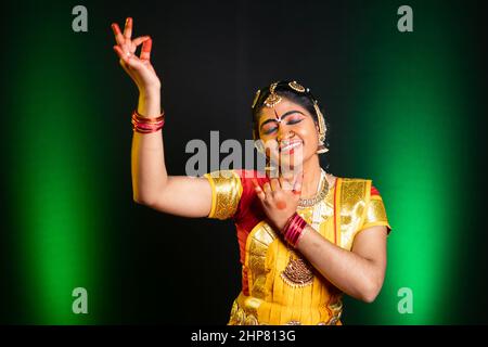 Indische bharathanatyam-Tänzerin in krishna Pose oder Geste mit geschlossenem Auge auf der Bühne während der Performance - Konzept der indischen Kultur, traditionelle Kleidung und Stockfoto