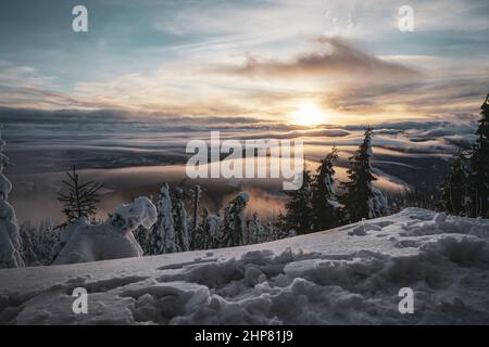 Verschneite Spitze des Berges in Europa mit Sonnenuntergang und Low Clouds Inversion Stockfoto