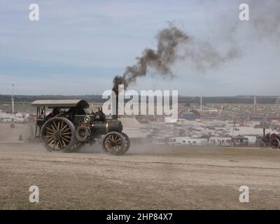 Auf der großen Dampfmesse dorset in england fährt eine historische Dampftraktormaschine mit einer großen Rauchwolke auf einer Straße auf einem Hügel Stockfoto