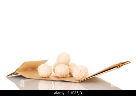 Einige süße Kokosnussbonbons auf einer Papiertüte, Makro, isoliert auf weißem Hintergrund. Stockfoto
