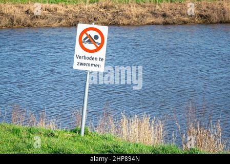 Schild mit der Aufschrift „Verbotenes Schwimmen“ (Niederländisch: Verbunden te zwemmen) in der Nähe eines Flusses Stockfoto