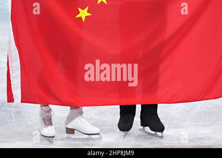 Peking, China. 19th. Februar 2022. Die Schlittschuhe von Wenjing Sui und Cong Han aus China ragen hinter der chinesischen Flagge hervor, als sie eine Siegerrunde machen, nachdem sie am Samstag, den 19. Februar 2022, den Pairs Figure Skating Wettbewerb im Hauptstadtstadion bei den Olympischen Winterspiele 2022 in Peking gewonnen haben. Wenjing Sui und Cong Han aus China gewannen das Gold, Evgenia Tarasova und Vladimir Morosov aus Russland, die Silbermedaille und Anastasia Mishina und Aleksandr Gallamov aus Russland die Bronze. Foto von Richard Ellis/UPI Credit: UPI/Alamy Live News Stockfoto