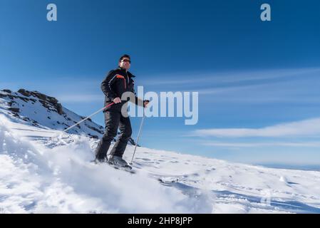 Skifahrer, die im Skigebiet auf dem Schnee den Berg hinunter gleiten Stockfoto