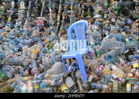 KENIA, Nairobi, Kibera Slum, Plastikflaschen von Nestle, Pepsico, Coca Cola and Co., Dumping, Getränkehersteller ersetzen Mehrwegglasflaschen mehr und mehr durch Einwegglasflaschen, aufgrund fehlender Recyclingsysteme wachsen und wachsen die Abfallberge, in der Mitte ein Plastikstuhl Monobloc / KENIA, Nairobi, Kibera Slum, Plastikflaschen von Coca Cola und Co, Coca Cola reduziert in Afrika die Glaspfandflaschen zunehmend und steigt dafür mehr auf den Verkauf von Einwegflaschen aus Plastik um, die Müllberge wachsen, Recycling Systeme fehlen, dazwischen ein Plastikstuhl Monobloc Stockfoto