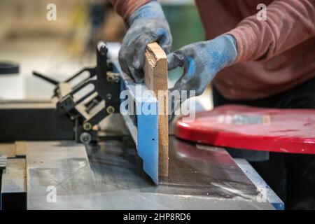 Mann schneidet Holzstücke mit Tischsäge in der Holzwerkstatt Stockfoto