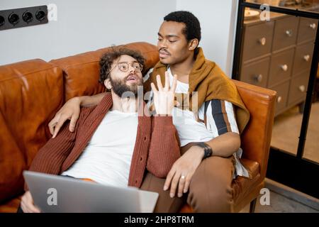 Männlich Gay paar im Gespräch auf einer Couch zu Hause Stockfoto
