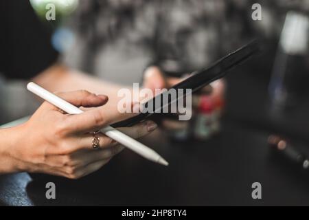 Portrait einer professionellen Tätowiererin in einem Tattoo-Studio zeichnet eine Skizze auf ein Tablet Stockfoto