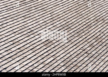 Verwittert und verblasst von der Sonne, Regen und Schnee Holzschindeln, die die Fassade eines alpinen Hauses sind. Holzstruktur in Grau- und Orange-Tönen. Stockfoto