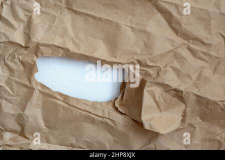 Loch in Papier mit farbigem Papierhintergrund innen. Gute Papiertextur.eingerissene Öffnung im Papier.Papier gerissen, um ein Loch zu schaffen Stockfoto