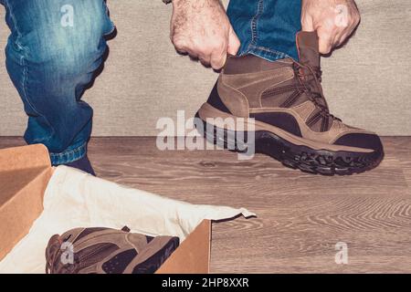 Schuhmontage. Ein Mann zog neue Schuhe an. Männliche Hände halten einen Stiefel. Konzepteinkäufer. Shopper, Einkaufskonzept. Nahaufnahme. Stockfoto