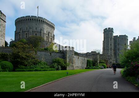 Ein männlicher Besucher auf der Castle Hill Road zum Eingang von Windsor Castle. Der Rundturm und der Edward III Turm stehen über den Burgmauern. Stockfoto