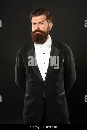 Eleganter Butler in Smoking auf schwarzem Hintergrund, formalwear Stockfoto