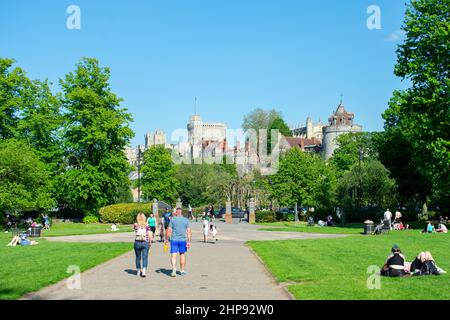 Windsor Castle dominiert die Aussicht von den Alexandra Gardens in Windsor, in der britischen Grafschaft. Die Menschen schlendern durch den Park in Richtung der Stadt Windsor. Stockfoto