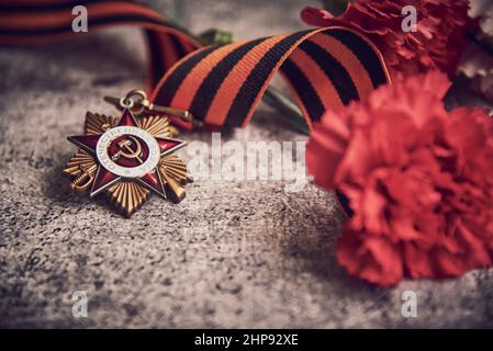 Victory Day Mai 9 Feiertagshintergrund Komposition, sowjetische Ordnung mit russischem Text ins Englische übersetzt als Patriotischer Krieg, Zweiter Weltkrieg,Nelke Stockfoto