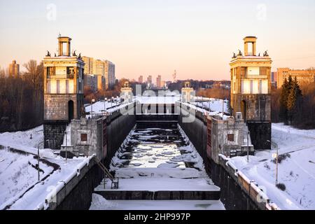 Schleusen auf dem Moskauer Kanal am Moskwa-Fluss im Winter, Moskau, Russland. Luftaufnahme der sowjetischen Schleusentore im Nordwesten der Stadt. Skyline von Moskau bei Sonnenuntergang. Stockfoto