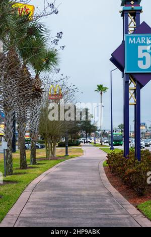 Kissimmee, Florida - 6. Februar 2022: Vertikale Weitwinkelansicht eines Gehwegs neben dem Irlo Bronson Memorial Highway an einem wolkigen Tag. Stockfoto