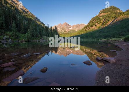 Maroon Bells, kristallklarer Maroon Lake und wunderschöne Sommerreflexionen am frühen Morgen in der Nähe von Aspen, Colorado Stockfoto