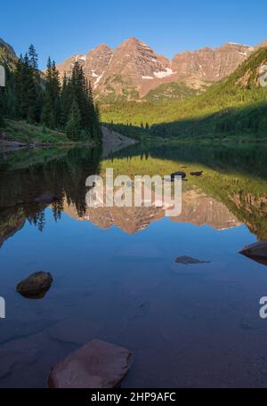 Maroon Bells, kristallklarer Maroon Lake und wunderschöne Sommerreflexionen am frühen Morgen in der Nähe von Aspen, Colorado Stockfoto