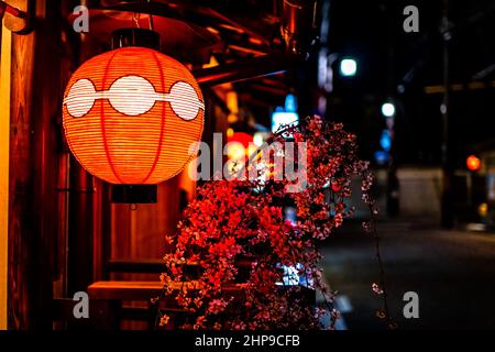 Kyoto, Japan Bunte Straße Straße Gasse in Gion Bezirk am Abend mit Nahaufnahme von beleuchteten traditionellen roten Papier Laterne Lampe und Kirsche BL Stockfoto