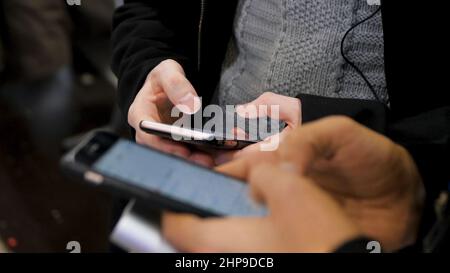 Nahaufnahme von Smartphones in den Händen von zwei jungen Männern. Neue Generation in einem Café aus nächster Nähe. Kommunikationskonzept. Paar mit digitalen Gadgets für onli Stockfoto