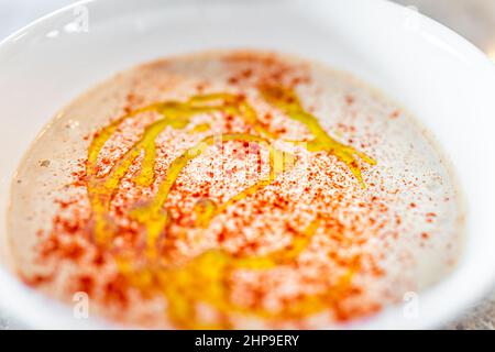 Oben Ansicht Makro Nahaufnahme von Hummus verteilt hausgemachte mit Kichererbsen Paprika Harissa Gewürze und Knoblauch in einer weißen Schüssel mit beträufigem Olivenöl auf der Oberseite Stockfoto