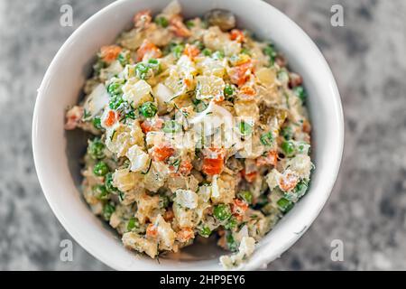 Traditioneller ukrainischer oder russischer Salat namens Olivie olivier Macro Closeup mit gekochten gewürfelten Kartoffeln, Karotten, Erbsen und Zwiebeln in Mayonnaise Stockfoto