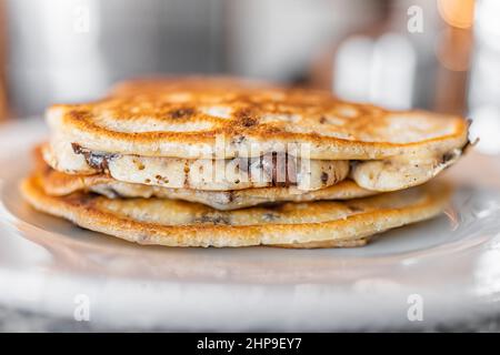 Makroansicht der Seitenansicht von Buttermilch-Pfannkuchen mit dunklem Schokoladenchip auf dem Teller als traditionelles Frühstücksbrunch-Dessert Stockfoto