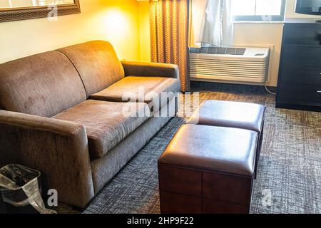 Hotel-Suite oder Studio-Zimmer Sofa Couch Lampe Wohnzimmer in modernen Hotel Motel Zimmer mit niemand keine Menschen im Inneren mit Fußstütze komfortable furn Stockfoto