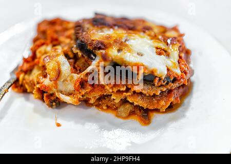 Italienische Fleisch Auberginen Parmesan Lasagne mit geschmolzenem Käse und Gemüse auf weißem Teller für das Abendessen mit Textur Makro Nahaufnahme der roten Marinara-Sauce Stockfoto