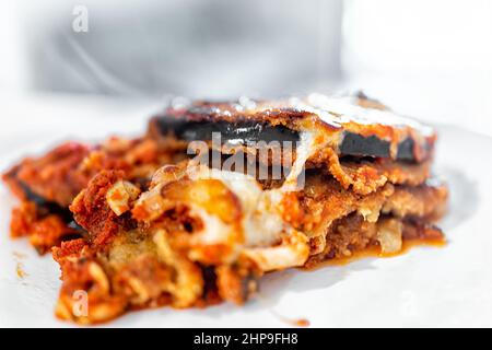 Italienische Auberginen-Parmesan-Lasagne mit geschmolzenem Käse und Gemüse auf weißem Teller zum Abendessen mit Textur-Makro-Nahaufnahme von der roten Marinara-Sau Stockfoto