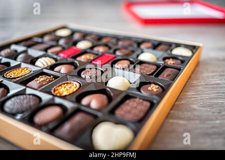 Schachtel Pralinen Trüffel Gourmet Milch und dunkle Süßigkeiten Bonbons Paket mit verschiedenen Herzformen Vielfalt Seite Nahaufnahme mit Deckel im Hintergrund Stockfoto