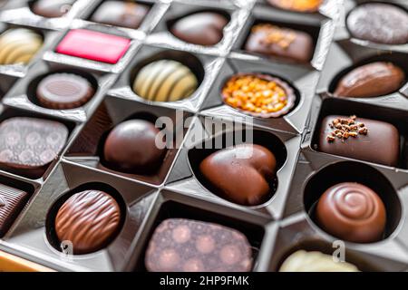 Makro-Nahaufnahme einer Schachtel Pralinen-Trüffel mit luxuriöser Gourmet-Milch und dunklen Desserts mit verschiedenen Herzformen Stockfoto