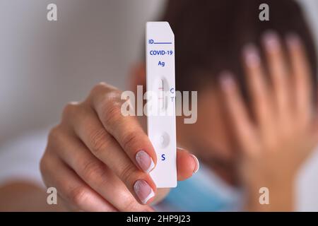 Traurige Frau mit schnellem Covid-Antigen-Test oder Express-Covid-Test mit positivem Coronavirus-Ergebnis. Frau mit Covid-19-Infektion Stockfoto