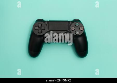 Schwarzer Gaming-Controller auf türkisfarbenem Hintergrund isoliert. Stockfoto