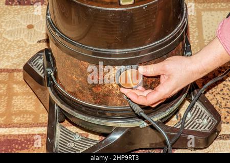 Der Prozess der Reinigung des Teppichs mit einem Staubsauger mit einem Wasserfilter. Die Hand einer Frau öffnet ein Loch, um Luft in einen Staubsauger zu blasen. Stockfoto