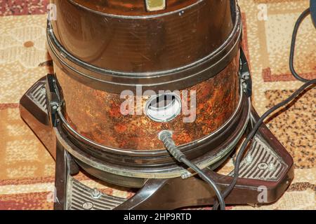 Der Prozess der Reinigung des Teppichs mit einem Staubsauger mit einem Wasserfilter. Die Hand einer Frau öffnet ein Loch, um Luft in einen Staubsauger zu blasen. Stockfoto