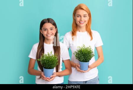 Glückliche Frau Mutter und adoptierte Tochter Kind lächeln mit Topfpflanzen blauen Hintergrund, Pflege Stockfoto