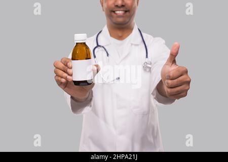 Indischer Mann Arzt Hält Husten Sirup Zeigt Daumen Nach Oben Nahaufnahme Isoliert Stockfoto