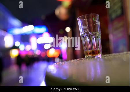 Hamburg, Deutschland. 20th. Februar 2022. Auf einem Tisch vor einer Kneipe auf der Großen Freiheit bei der Reeperbahn steht ein gebrautes Glas. In Hamburg trat am Samstag die erste Stufe der dreistufigen Aufhebung aller Corona-Maßnahmen in Kraft. Geimpfte und wiedergeborene Menschen können sich seit Mitternacht wieder in unbegrenzter Zahl privat treffen. Darüber hinaus wurden das Alkoholverbot für Einzelhändler und die Ausgangssperre im Gastronomiegewerbe aufgehoben. Quelle: Jonas Walzberg/dpa/Alamy Live News Stockfoto