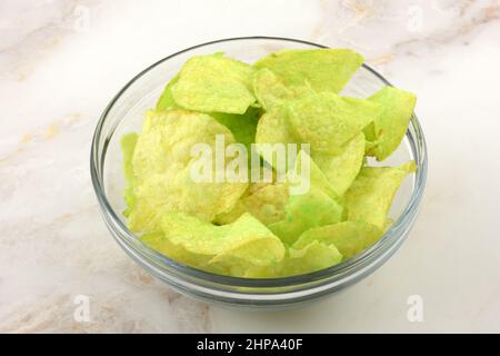Grüne Wasabi-Kartoffelchips in einer Glas-Snack-Schüssel auf dem Tisch Stockfoto
