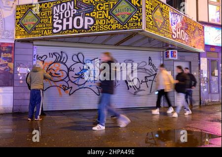 Hamburg, Deutschland. 20th. Februar 2022. Passanten laufen an einem geschlossenen Kiosk auf der Reeperbahn vorbei. In Hamburg trat am Samstag die erste Stufe der dreistufigen Aufhebung aller Corona-Maßnahmen in Kraft. Geimpfte und wiedergeborene Menschen können sich seit Mitternacht wieder in unbegrenzter Zahl privat treffen. Darüber hinaus wurden das Alkoholverbot für Einzelhändler und die Ausgangssperre im Gastronomiegewerbe aufgehoben. Quelle: Jonas Walzberg/dpa/Alamy Live News Stockfoto