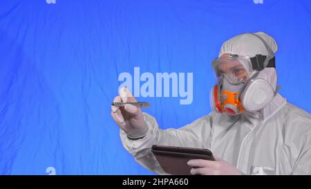 Wissenschaftler Virologe in Atemschutzmaske macht schreiben in einem Tablet-Computer mit Stift. Mann trägt eine medizinische Schutzmaske. Konzept Gesundheit Sicherheit Virus cor Stockfoto