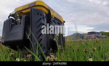 Nahaufnahme von Gas Diesel mobile tragbare Stromgenerator arbeiten auf Gras. Der tragbare Generator mit Benzinkraftstoff gibt elektrischen Energiestrom für ab Stockfoto