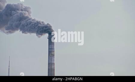 Dieser Rauch kommt aus dem Kamin in einer Fabrik. Schädliche Emissionen aus dem Rohr in die Atmosphäre. Schwere Schäden an der Umwelt. Coaling Station für Werkstapel. Nahaufnahme. Dunkle traurige Aussicht. Stockfoto