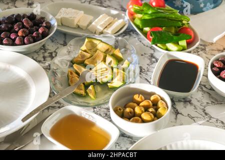 Selektiver Schwerpunkt des traditionellen türkischen Frühstücks, Käse, Honig, Oliven, Traubenmelasse, Und Gemüse serviert in der Morgensonne. Stockfoto